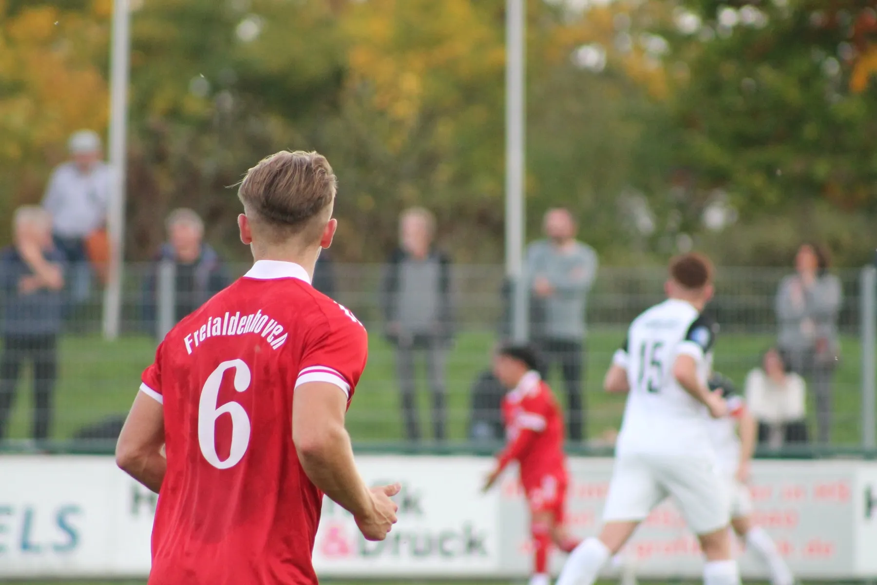 Spieler mit der Rückennummer 6 im roten Trikot beobachtet das Spielgeschehen